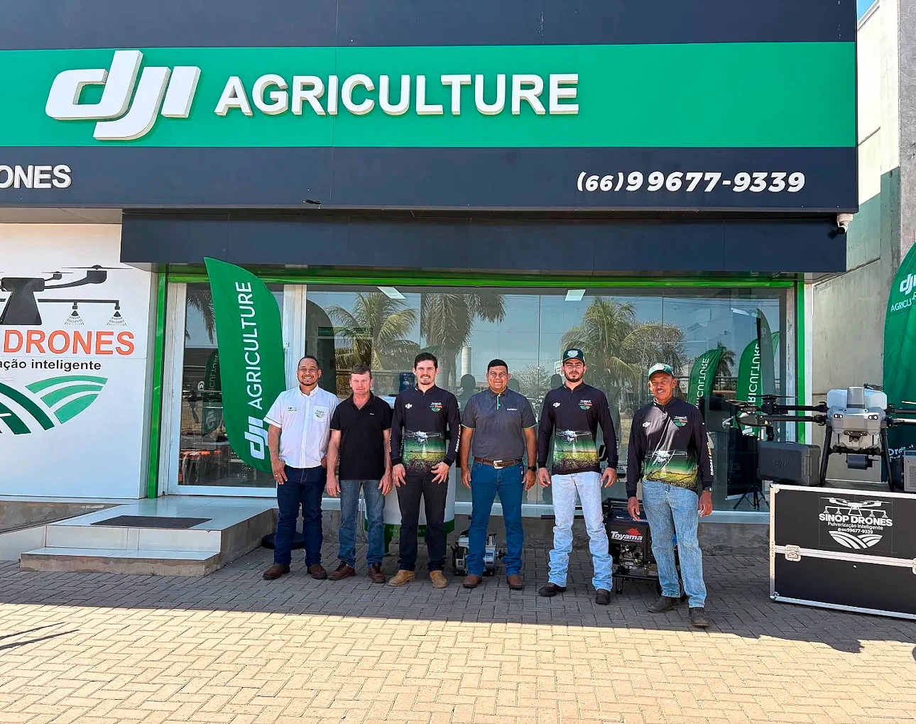 Equipe da Sinop Drones em frente à loja, ao lado de um drone agrícola